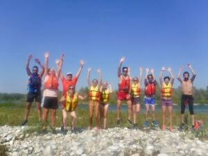 Gruppo di insegnanti che salta su una spiaggia durante l'aggiornamento insegnanti rafting sul fiume Ticino